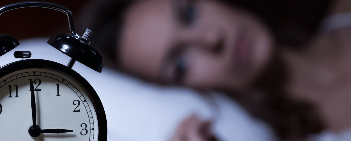 Vrouw die 's nachts wakker ligt en naar haar wekker kijkt/Femme éveillée la nuit regardant son réveil